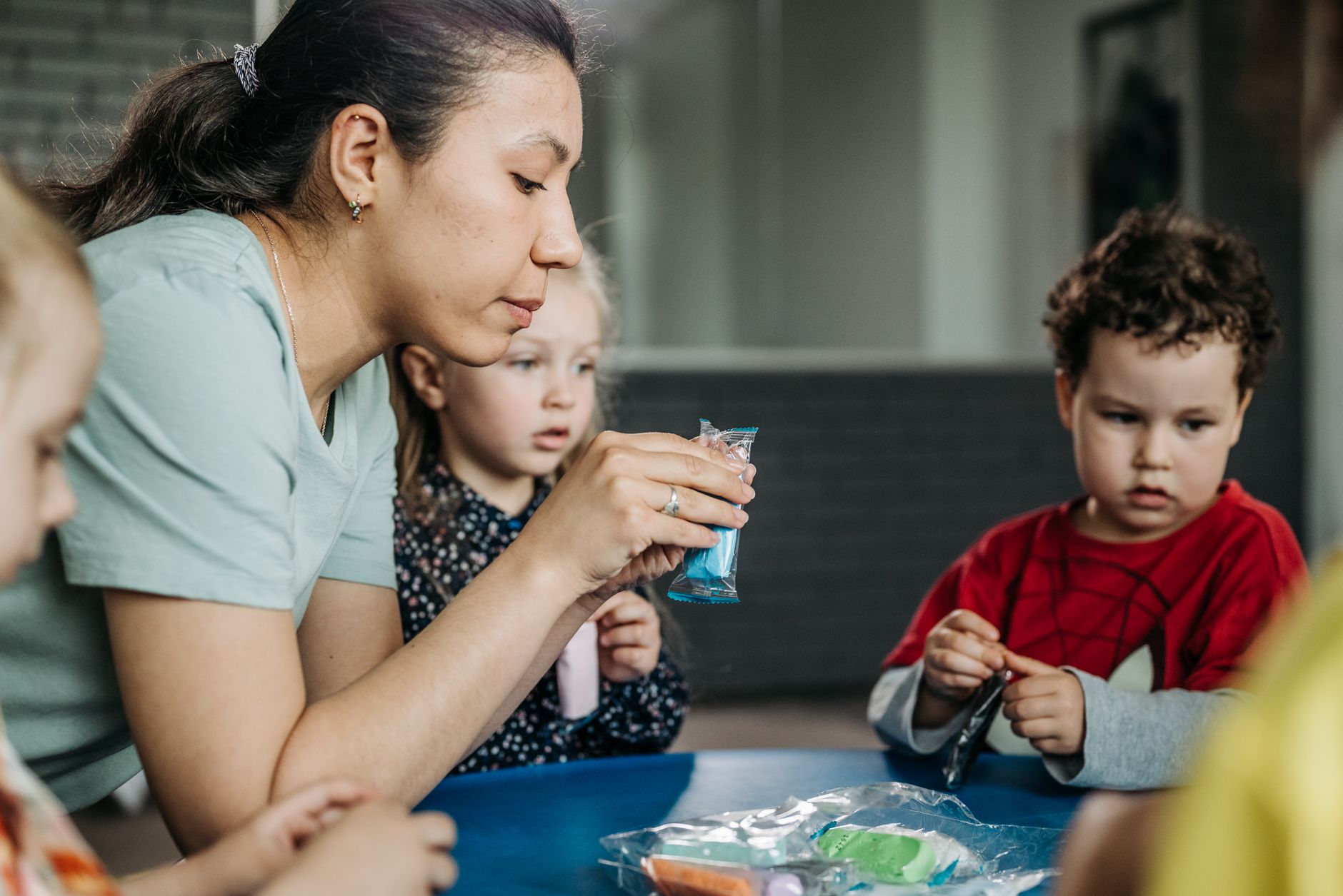 Teacher and children working together at a classroom table, documentary style.